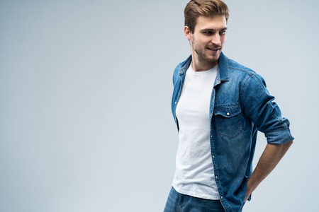 Portrait of stylish, stunning man in denim outfit standing over grey background.の写真素材