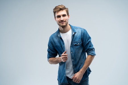 Portrait of stylish, stunning man in denim outfit standing over grey background.の写真素材