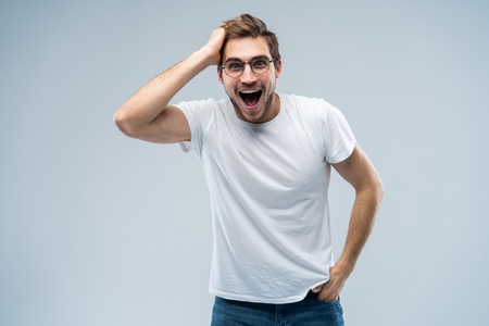 Portrait of young amazed man isolated on gray background.