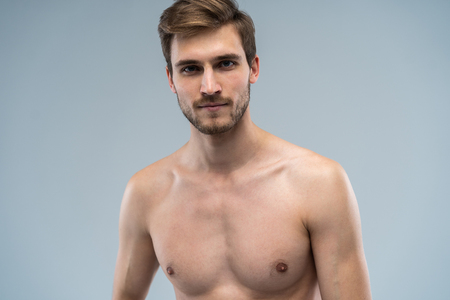 portrait of attractive confident concentrated focused seductive guy with ideal face features bearded with stylish trendy hairdress isolated on gray.の写真素材