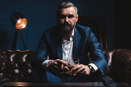Attractive man with cigar and a glass whiskeyの写真素材