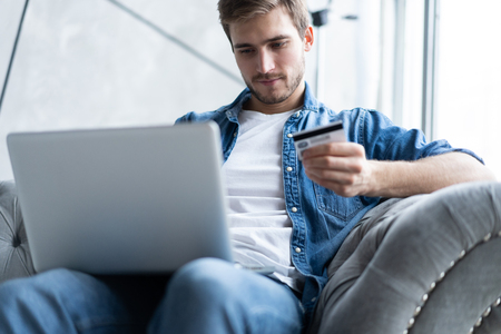 technology, shopping, banking, home and lifestyle concept - close up of man with laptop computer and credit card at home.の写真素材