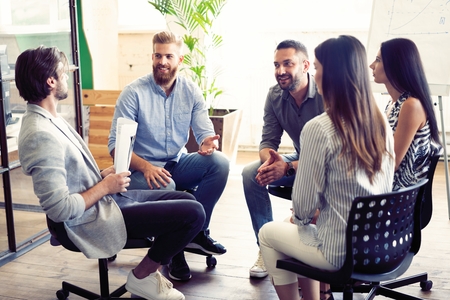 Teamwork is a key to success. Business people in smart casual wear talking and smiling while having...