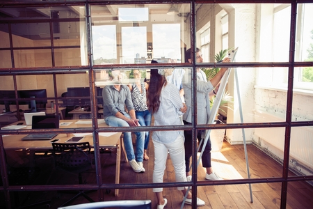 Achieving best results. Modern young man conducting a business presentation while standing behind the glass wall in the board room.の写真素材