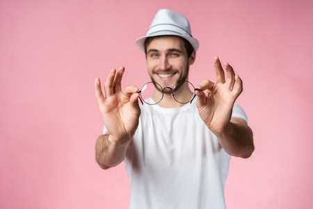 Cheerful hipster guy smiles happily, has excited expression, dresssed casually isolated over pink...
