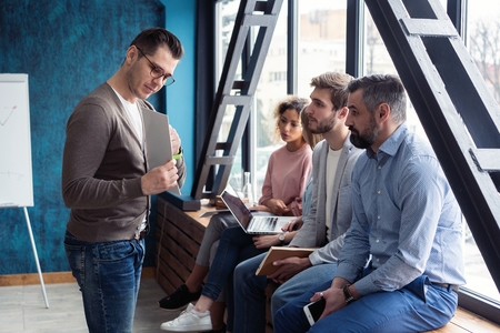 Shot of a male office worker giving creative presentation to his colleagues. Businessman explaining business plan to coworkers in officeの写真素材