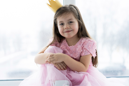 Cute little girl in a princess costume. Pretty child preparing for a costume party. Beautiful queen in gold crown.の写真素材