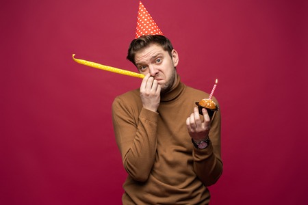 Picture of unhappy stressed young man having unhappy look, feeling tired and worn out with birthday...