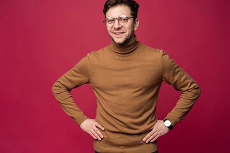 A confident young man in a studio, wearing glasses