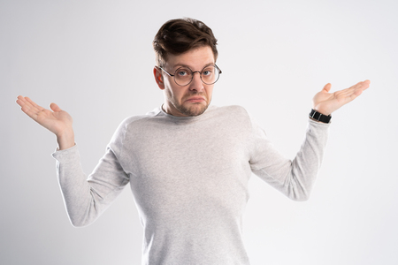 Young emotional careless man isolated on white background with copy space for text put his head on his fist and look aside stand in casual outfitの写真素材