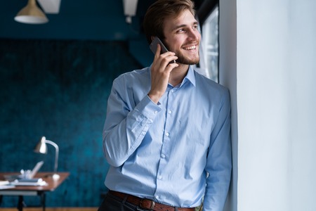 handsome businessman in suit standing and talking on smartphone