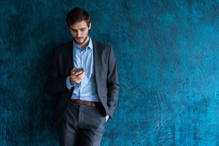 handsome young bearded business man in office using mobile phone indoors.の写真素材