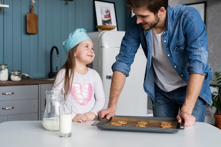 father and daughter making cookies in kitchen