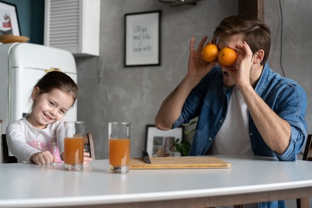 family, eating and people concept - happy father and daughter having breakfast at homeの写真素材