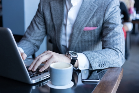 Full concentration. Good looking young man in full suit using computer while sitting in the cafeの写真素材