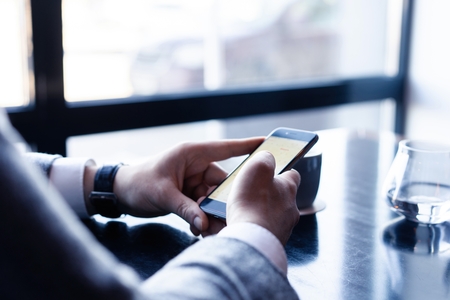 Business man holding smartphone, using application to booking suite in hotel for business trip,...