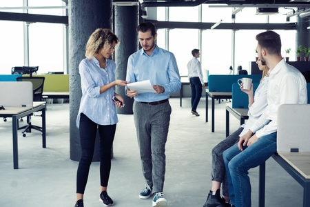 Taking their business on the move. Full length of young modern people in smart casual wear having a discussion while walking through the large modern office.の写真素材
