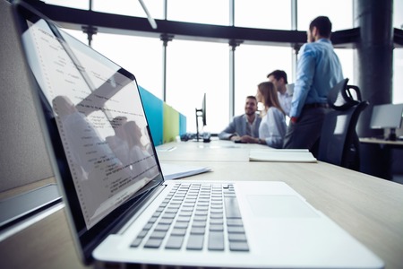 Close-up of workplace in modern office with business people behind. Colleagues meeting to discuss their future financial plans.の写真素材
