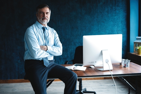 Concentrated at work. Focused mature businessman working and taking notes in his modern office.