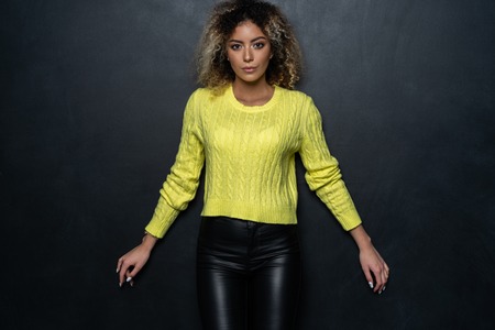 Portrait of a beautiful black female fashion model with curly hair over black background.の写真素材