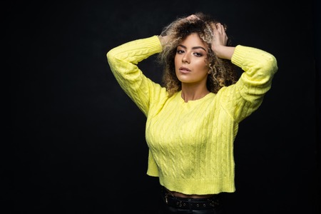 Portrait of a beautiful black female fashion model with curly hair over black background.