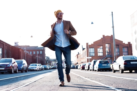 Fashion man portrait. Young man in glasses wearing coat walking down the street.の写真素材