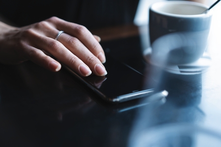 Close up of womens hands holding smartphone, female using mobile phone during coffee break.の写真素材