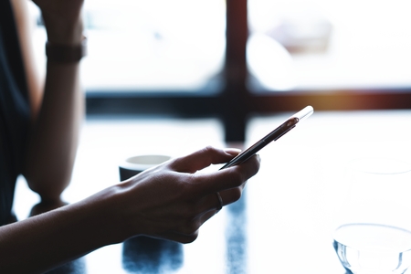 Close up of womens hands holding smartphone, female using mobile phone during coffee break.の写真素材