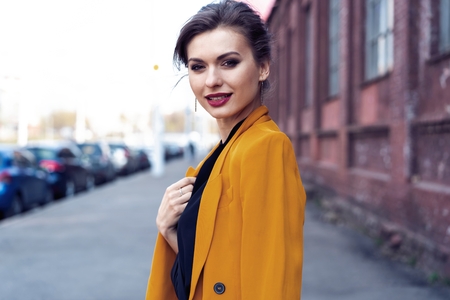 Portrait fashion woman walking on street . She wears yellow jacket, smiling to side.の写真素材