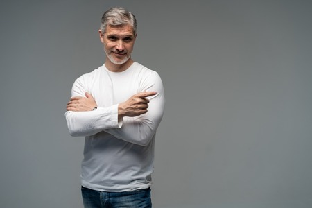 Handsome middle age senior man presenting and pointing with palm of hand looking at the camera over...
