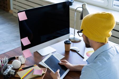 Young creative manager sitting at his table and working on computer