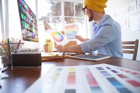 Young creative manager sitting at his table and working on computerの写真素材