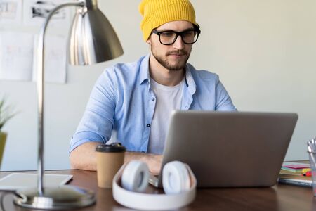 Enjoying his work. Skilled male IT professional freelancer working on clients project, using laptop computer and wireless internet.の写真素材