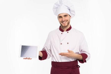 Portrait of a happy male chef cook showing blank tablet computer screen isolated on a white background.の写真素材