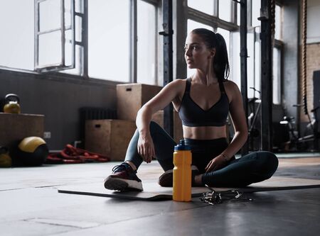 Strong muscular caucasian woman in the gym taking a break from a crossfit strength training in the...