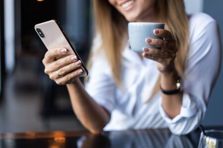 Young businesswoman using phone in coffee shopの写真素材