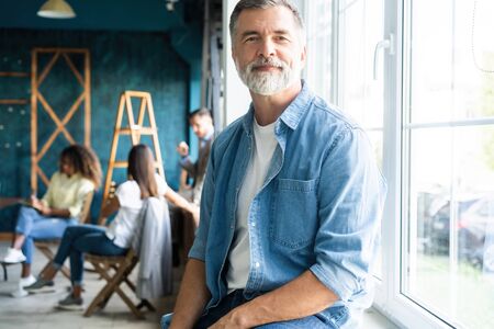 Smiling aged company boss posing in officeの写真素材