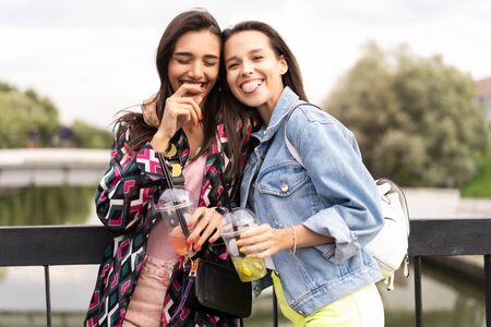 Hipster girlfriends drink cocktail in urban city backgroundの写真素材