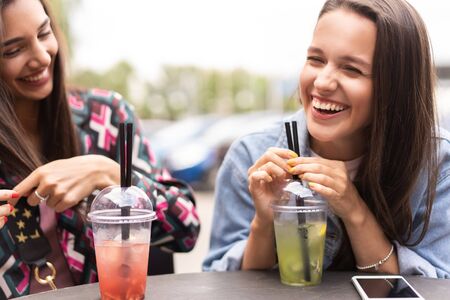 Hipster girlfriends drink cocktail in urban city backgroundの写真素材