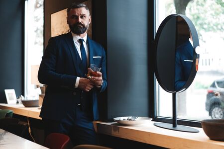 Stylish bearded man in a suit standing in modern office