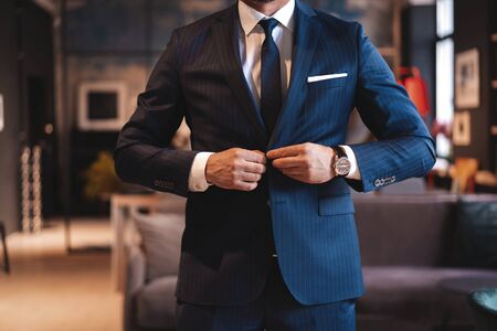 Handsome man adjusting his jacket while standing in modern office.の写真素材