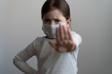 Stop coronavirus or covid 19 outbreak concept - young girl in medical protective mask shows a stop gesture with handの写真素材