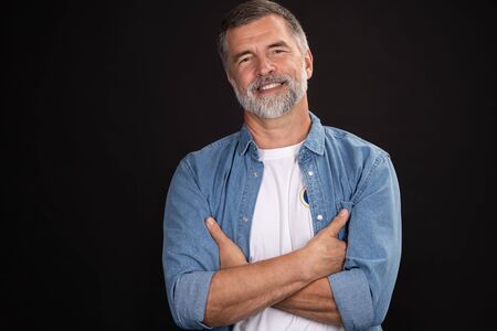 Portrait of smiling mature man standing on black background.の写真素材
