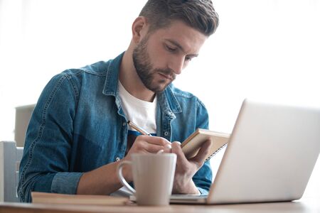 Handsome modern man designer working on laptop online, using internet at home