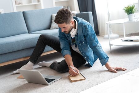 Handsome modern man designer working on laptop online, using internet at home