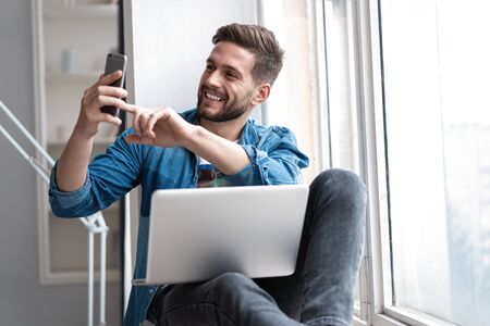Young happy man talking video call via smartphone at home.