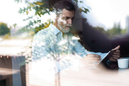 Happy mature businessman having coffee break in cafe.