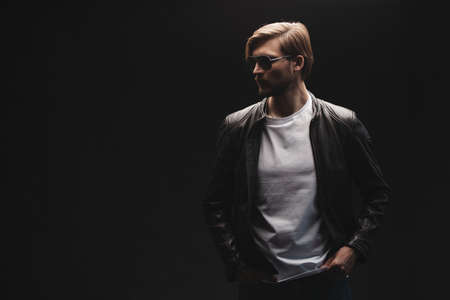 Fashion man, Handsome serious beauty male model portrait wear leather jacket, young guy over black background.の写真素材