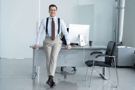 Portrait of a confident young businessman standing alone in a large modern office near his...