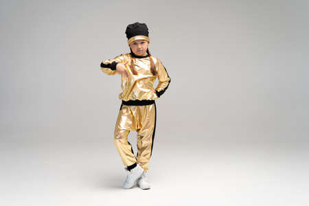 Happy little girl in gold suit dancing isolated on white background.